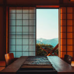 Traditional Japanese room with shoji sliding doors open to reveal a scenic mountain view and wooden deck chairs outside.