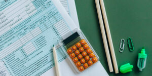 Tax documents with pencils, a calculator, and office supplies on a green background