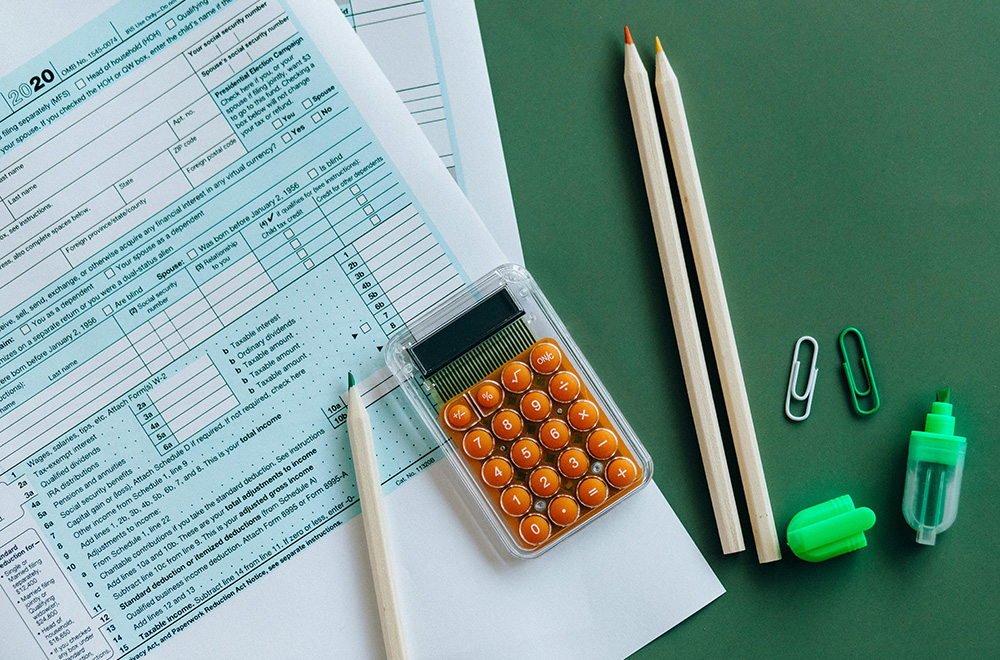 Tax documents with pencils, a calculator, and office supplies on a green background