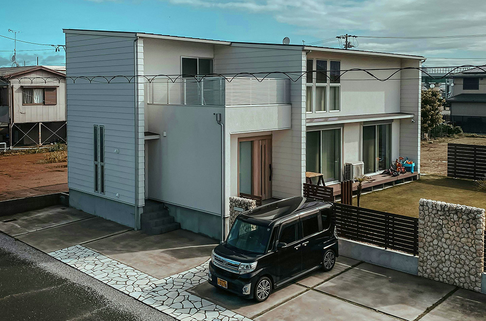 A small Japanese car parked in front of a traditional Japanese house, showcasing a harmonious blend of architecture and vehicle