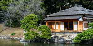 A quaint Japanese house perched on a small island, surrounded by tranquil waters, showcasing serene natural beauty