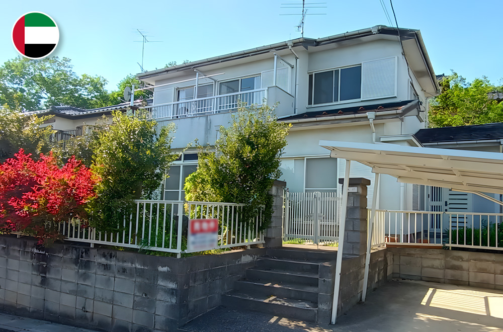 Spacious two-story Japanese house with a front garden, white exterior, gated entry, and covered carport in a sunny suburban area.
