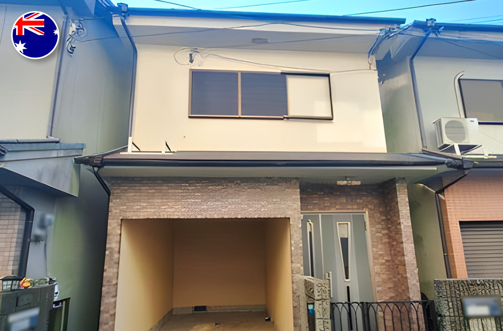 Two-story urban Japanese house with a built-in carport and modern facade, located between adjacent buildings.