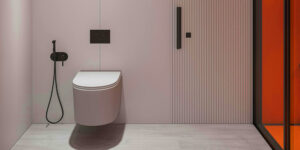 Minimalist modern bathroom with a wall-mounted toilet, matte black bidet spray, pale pink wall panels, light wood flooring, and an orange-tinted glass door.