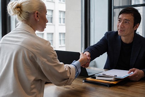 Japanese real estate consultant shaking hands with an international client during a property consultation in Japan.